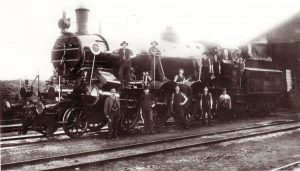Michael Unterguggenberger kam 1905 als Lokführer bei der Eisenbahn nach Wörgl – hier im Bild steht er mit Werkzeug in der Hand auf dem 3. Vorderrad, das Foto dürfte 1912 entstanden sein. Foto: Unterguggenberger Institut Archiv
